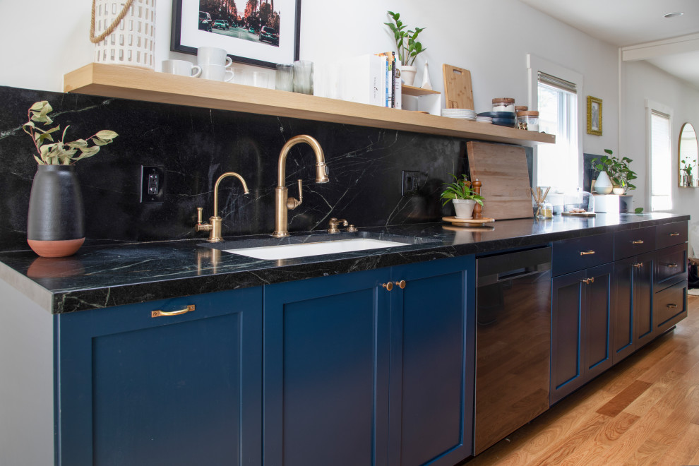 Medium sized classic galley kitchen/diner in Los Angeles with a submerged sink, beaded cabinets, blue cabinets, marble worktops, black splashback, marble splashback, stainless steel appliances, medium hardwood flooring, no island, brown floors and black worktops.