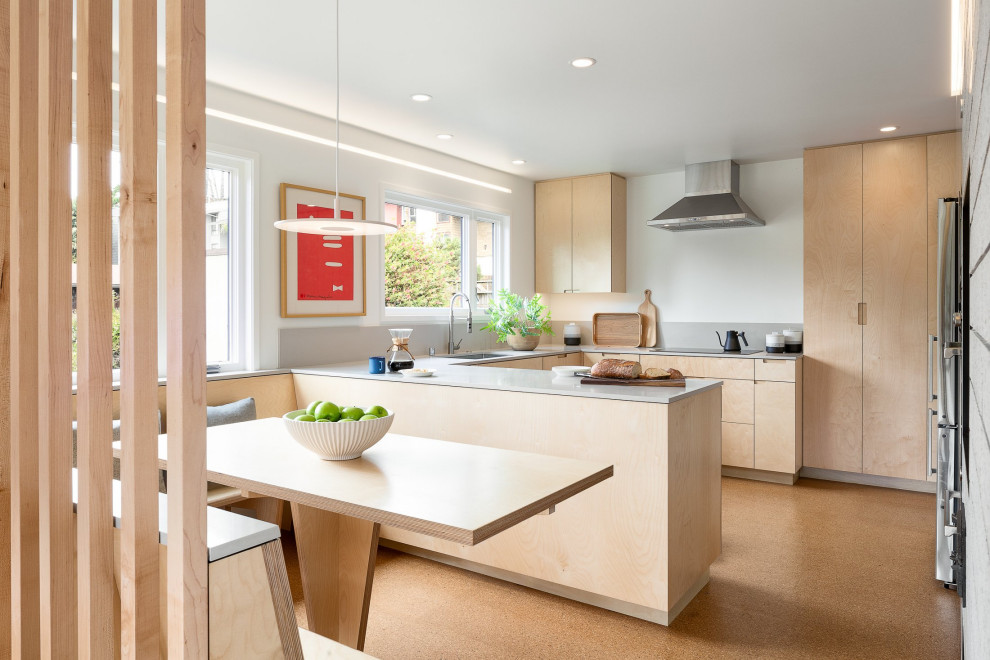 Foto di una cucina abitabile minimalista con ante in legno chiaro, elettrodomestici in acciaio inossidabile, pavimento in sughero, ante lisce e top grigio