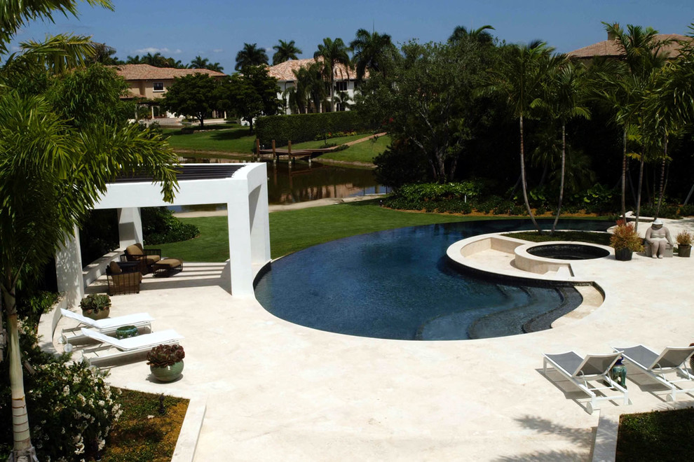Mid-sized contemporary backyard custom-shaped infinity pool in Miami with a hot tub and tile.