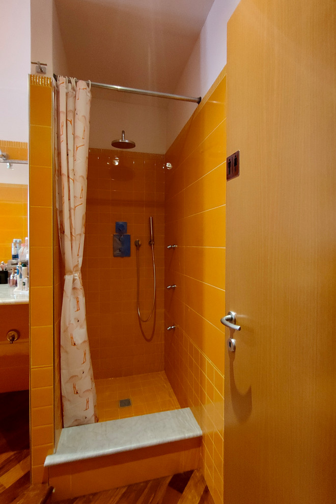 This is an example of a large eclectic 3/4 bathroom in Turin with open cabinets, an alcove shower, a wall-mount toilet, orange tile, porcelain tile, white walls, dark hardwood floors, an undermount sink, marble benchtops, brown floor, a shower curtain, white benchtops, a single vanity and a floating vanity.