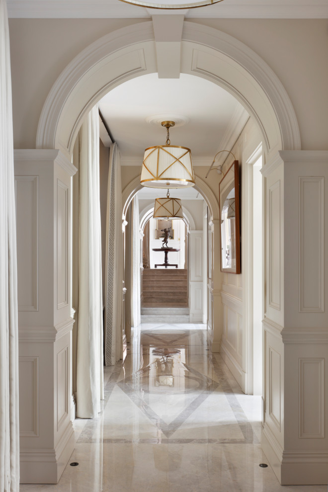 This is an example of a large traditional hallway in London with beige walls, beige floor and decorative wall panelling.