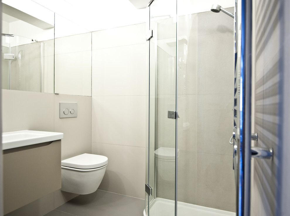 Small modern 3/4 bathroom in London with flat-panel cabinets, beige cabinets, a corner shower, a wall-mount toilet, beige tile, ceramic tile, white walls, ceramic floors and a wall-mount sink.