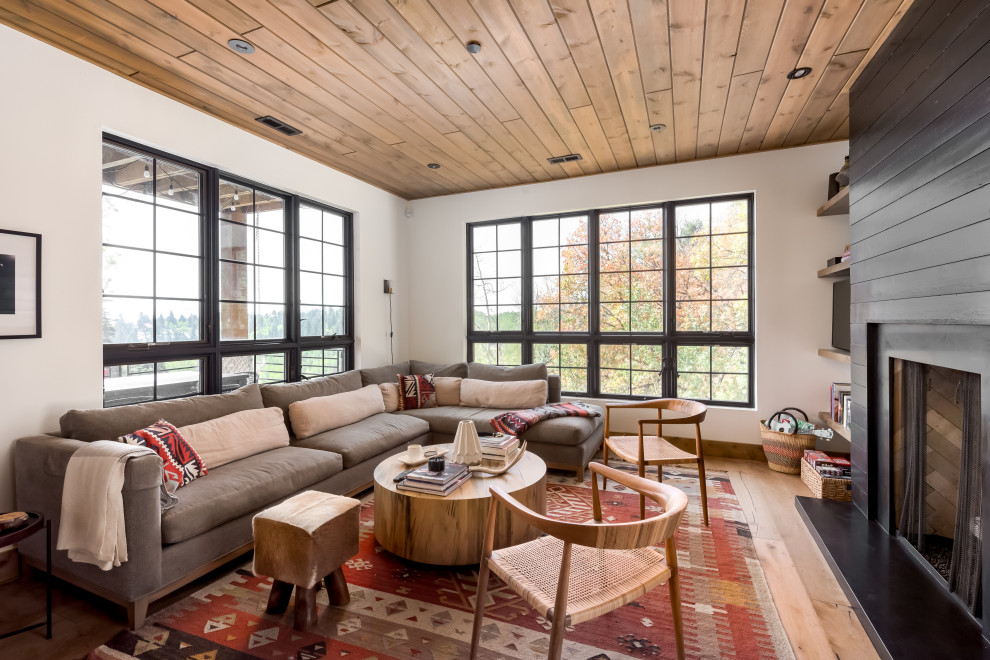 This is an example of a medium sized traditional open plan living room in Salt Lake City with white walls, light hardwood flooring, a standard fireplace, a timber clad chimney breast, a corner tv, brown floors and a timber clad ceiling.