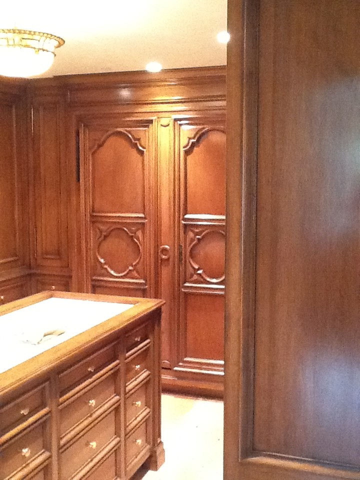 This is an example of a large traditional gender-neutral walk-in wardrobe in Santa Barbara with recessed-panel cabinets, dark wood cabinets and beige floor.