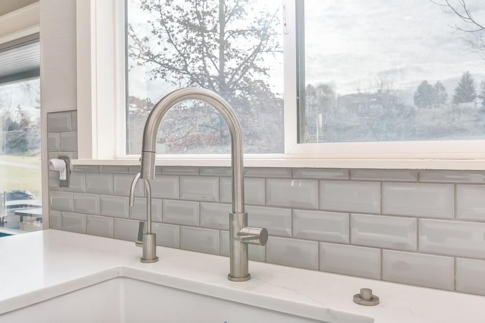 Mid-sized transitional u-shaped medium tone wood floor and brown floor eat-in kitchen photo in Boise with a farmhouse sink, shaker cabinets, white cabinets, quartz countertops, gray backsplash, subway tile backsplash, stainless steel appliances and an island