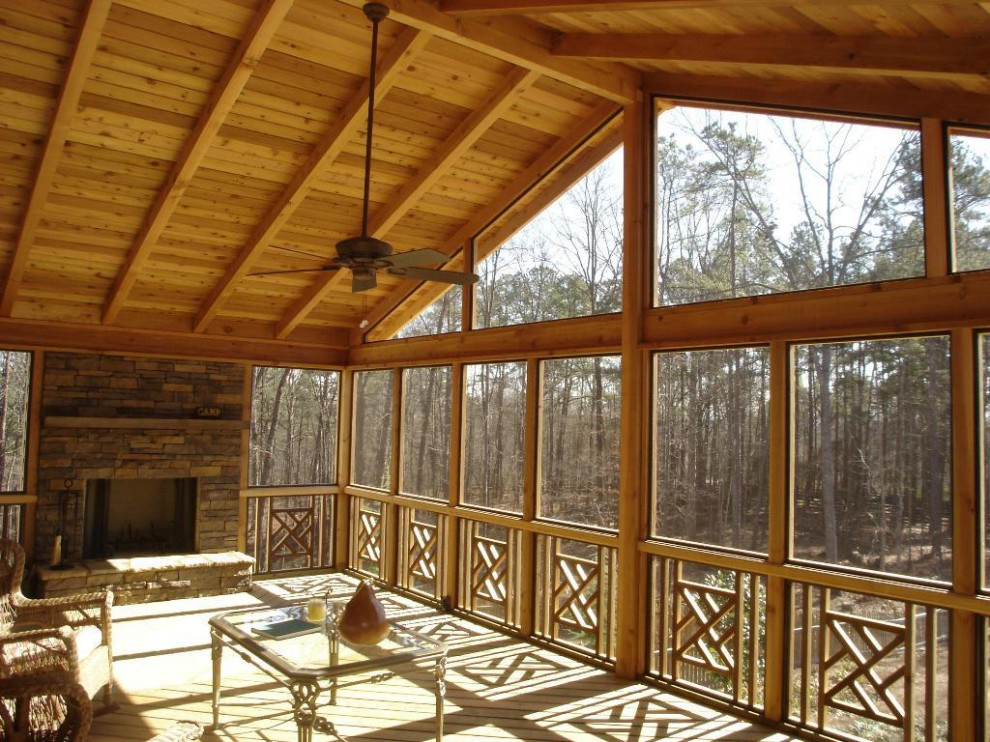 Cette image montre un très grand porche d'entrée de maison arrière chalet avec une cheminée, une extension de toiture et un garde-corps en bois.