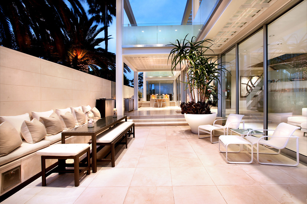 Design ideas for a large modern backyard patio in Orange County with tile and a roof extension.