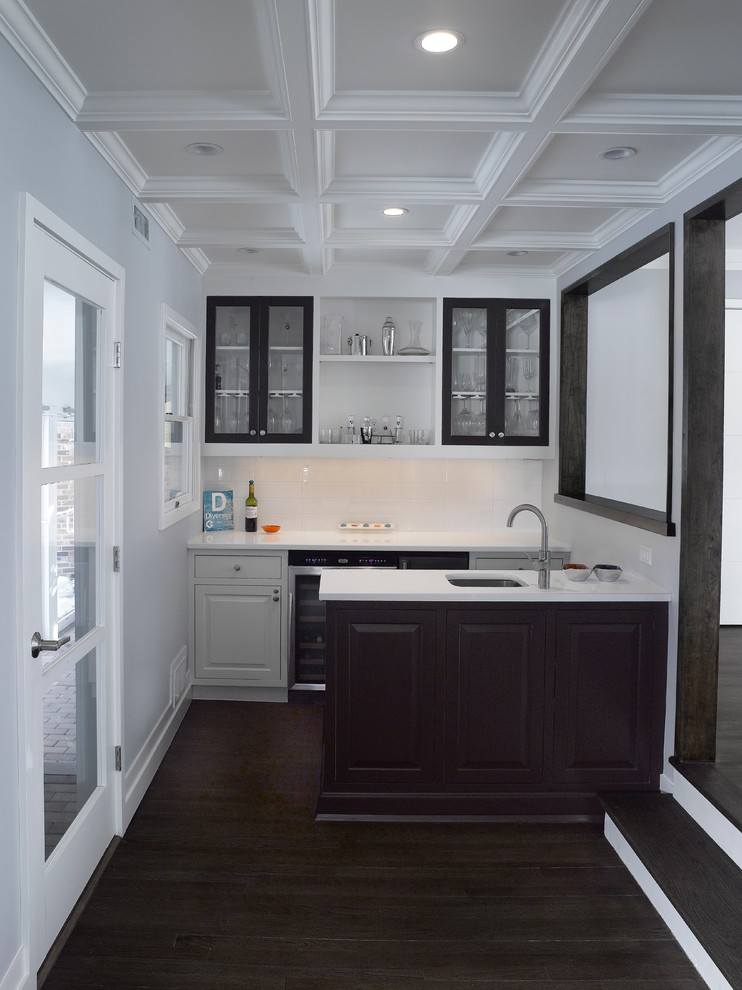 Wet bar - mid-sized transitional galley dark wood floor wet bar idea in New York with an undermount sink, glass-front cabinets, black cabinets, white backsplash and subway tile backsplash