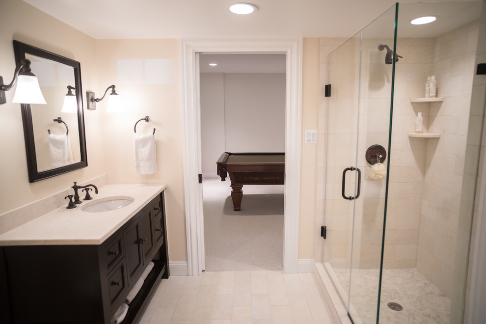 This is an example of a mid-sized traditional master bathroom in DC Metro with shaker cabinets, brown cabinets, an alcove shower, a one-piece toilet, beige tile, beige walls, an undermount sink, beige floor and a hinged shower door.