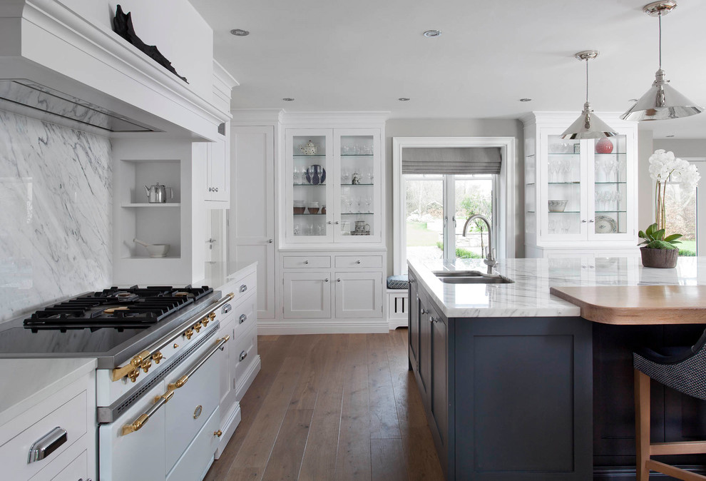 Photo of a large transitional u-shaped open plan kitchen in Dublin with shaker cabinets, white cabinets, marble benchtops, grey splashback, marble splashback, white appliances, medium hardwood floors, with island, brown floor and grey benchtop.