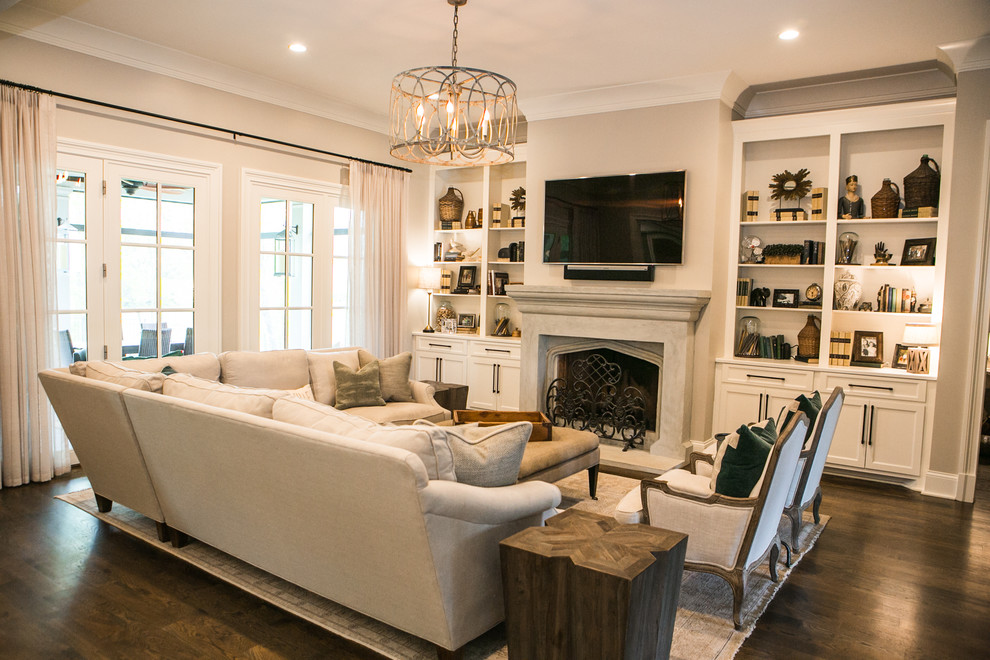 Large traditional open concept family room in Nashville with beige walls, medium hardwood floors, a standard fireplace, a tile fireplace surround, a wall-mounted tv and brown floor.