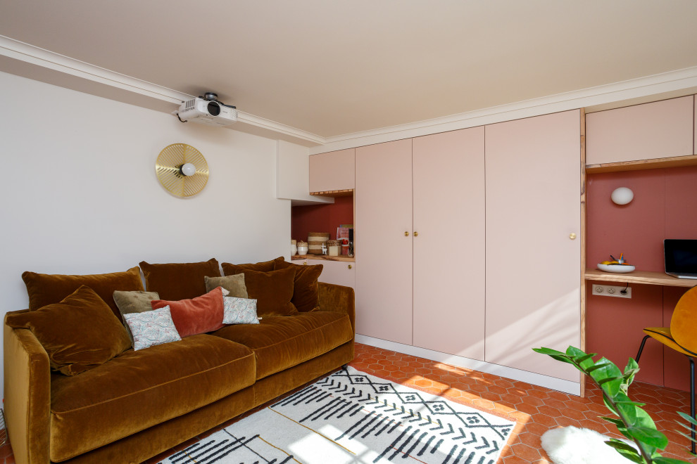 This is an example of a mid-sized mediterranean home theatre in Paris with terra-cotta floors, red floor, pink walls and a projector screen.