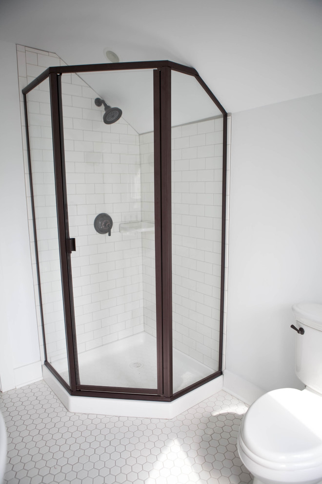 This is an example of a small transitional 3/4 bathroom in Kansas City with a wall-mount sink, flat-panel cabinets, white cabinets, a corner shower, white tile, ceramic floors, white walls, white floor, a hinged shower door, a two-piece toilet and subway tile.