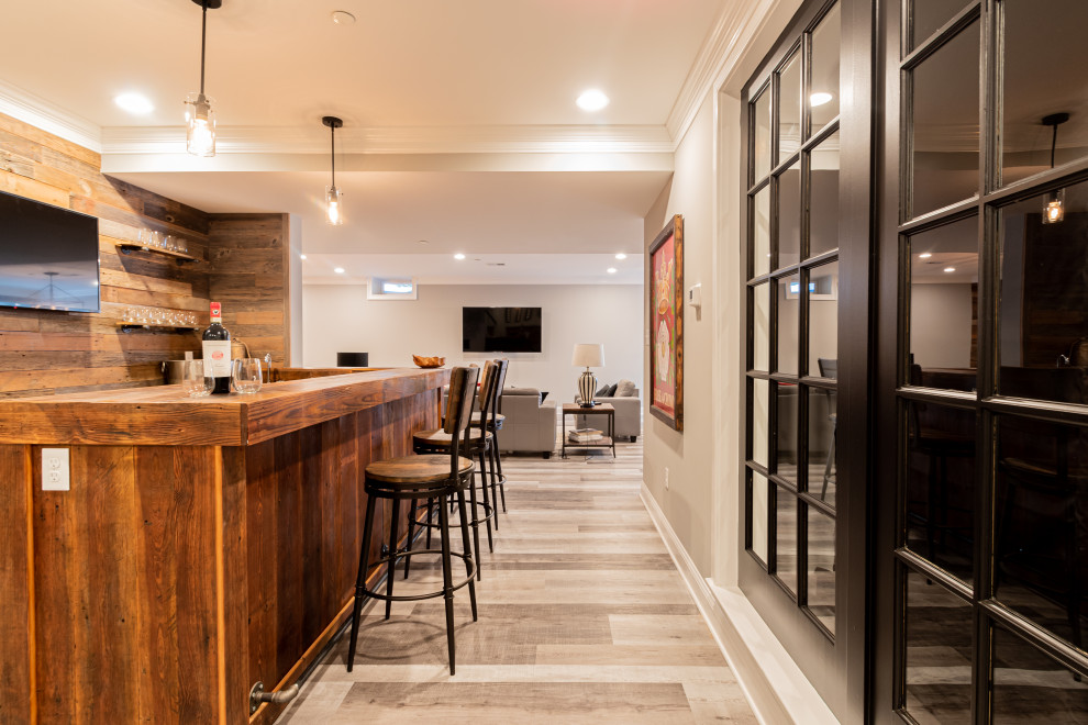 This is an example of a large country l-shaped wet bar in Philadelphia with a drop-in sink, distressed cabinets, wood benchtops, brown splashback, shiplap splashback, grey floor and brown benchtop.