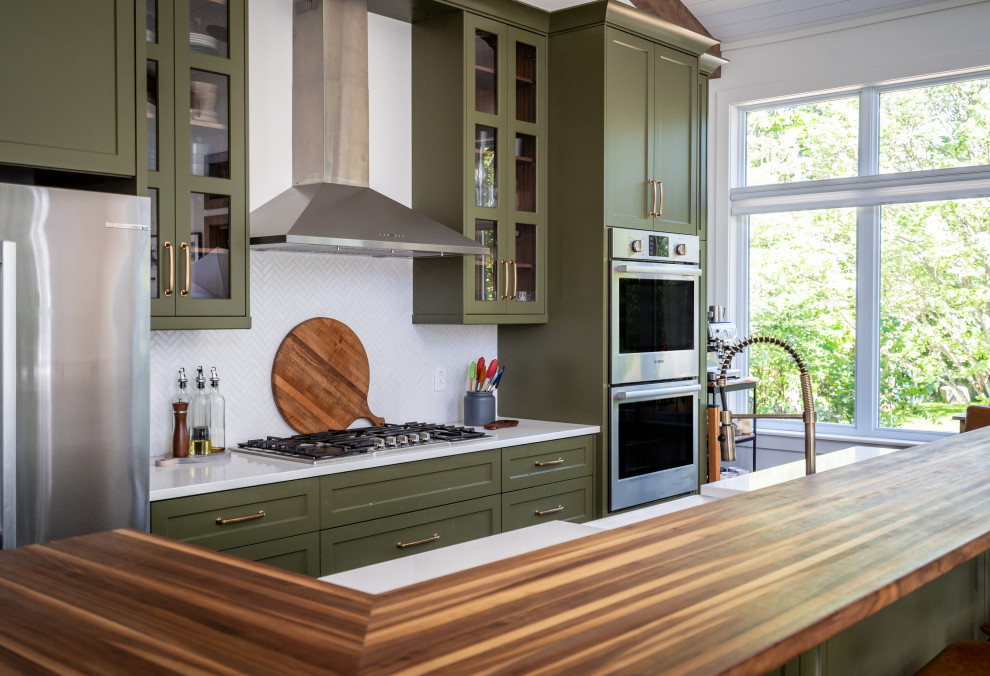 Example of a mid-sized transitional l-shaped eat-in kitchen design with an undermount sink, shaker cabinets, green cabinets, quartz countertops, white backsplash, ceramic backsplash, stainless steel appliances, an island and white countertops
