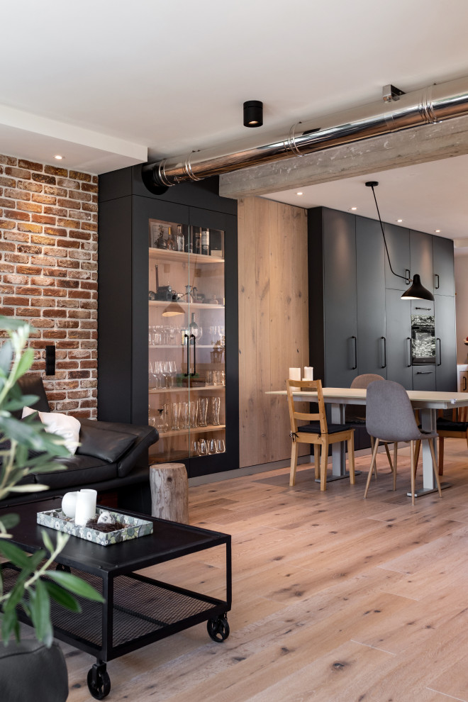 Cette photo montre une salle à manger ouverte sur la cuisine industrielle de taille moyenne avec un mur noir, un sol en bois brun, un sol bleu et un mur en parement de brique.