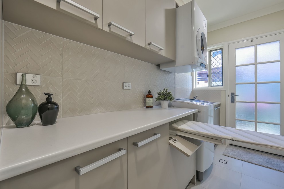 Mid-sized contemporary galley dedicated laundry room in Brisbane with a single-bowl sink, beige cabinets, laminate benchtops, beige walls, ceramic floors, beige floor and white benchtop.