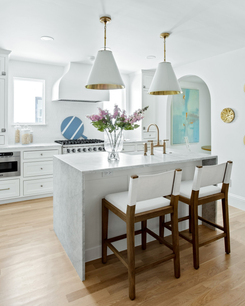 Inspiration för ett mellanstort vintage vit linjärt vitt kök och matrum, med en enkel diskho, skåp i shakerstil, vita skåp, marmorbänkskiva, vitt stänkskydd, stänkskydd i porslinskakel, rostfria vitvaror, ljust trägolv, en köksö och brunt golv
