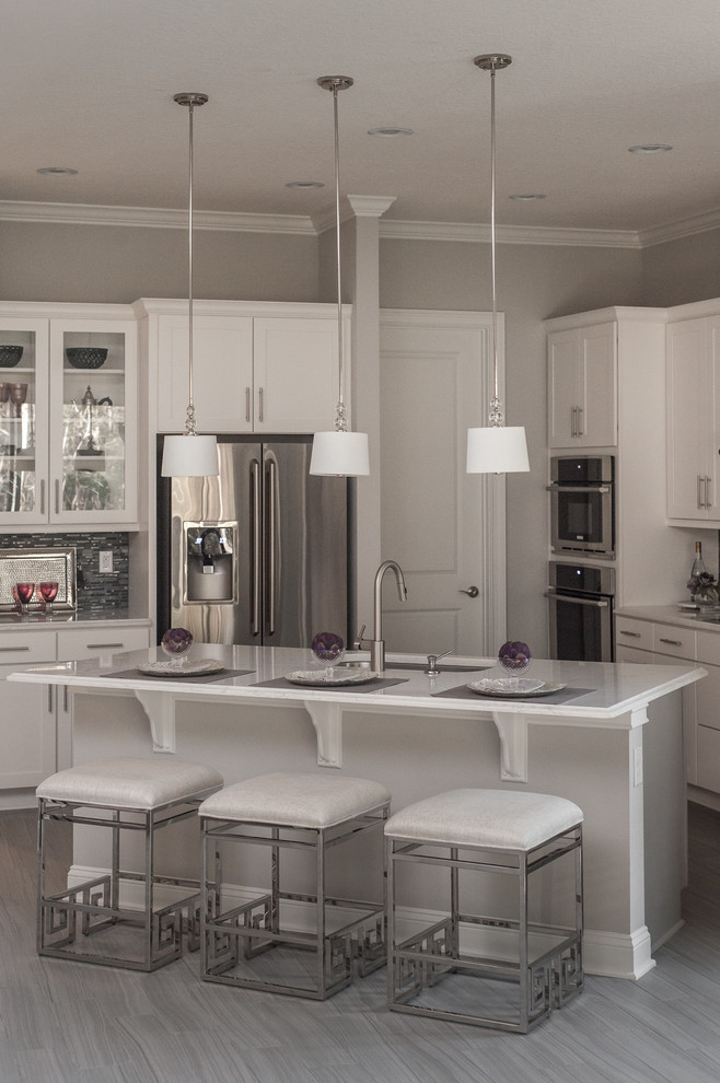 Example of a large transitional l-shaped ceramic tile eat-in kitchen design in Jacksonville with a drop-in sink, flat-panel cabinets, white cabinets, granite countertops, black backsplash, glass tile backsplash, stainless steel appliances and an island