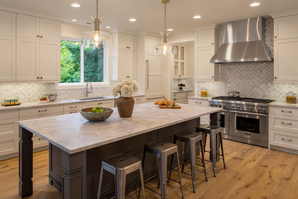 Mid-sized transitional l-shaped open plan kitchen in Seattle with an undermount sink, shaker cabinets, white cabinets, panelled appliances, medium hardwood floors, with island, marble benchtops, multi-coloured splashback and terra-cotta splashback.