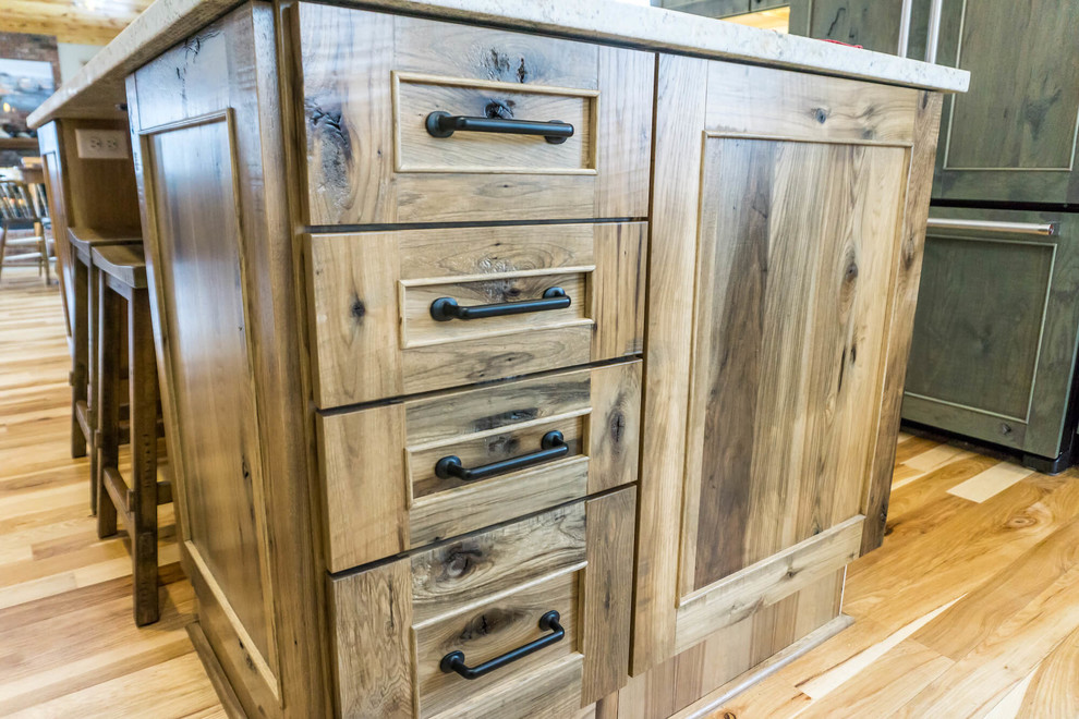 Example of a large mountain style light wood floor and brown floor open concept kitchen design with beaded inset cabinets, distressed cabinets, granite countertops, an island and white countertops