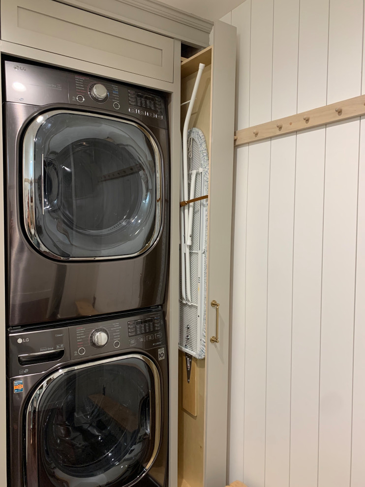 This is an example of a separated utility room with a belfast sink, shaker cabinets, beige cabinets, engineered stone countertops, a stacked washer and dryer and tongue and groove walls.