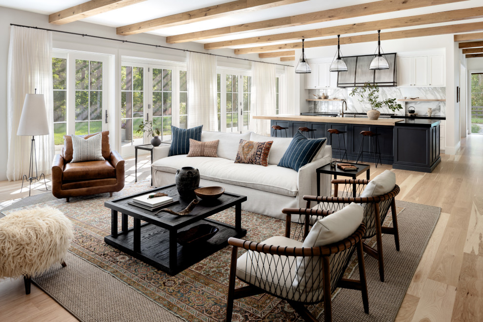 Example of a large country open concept light wood floor, beige floor and exposed beam living room design in DC Metro with white walls