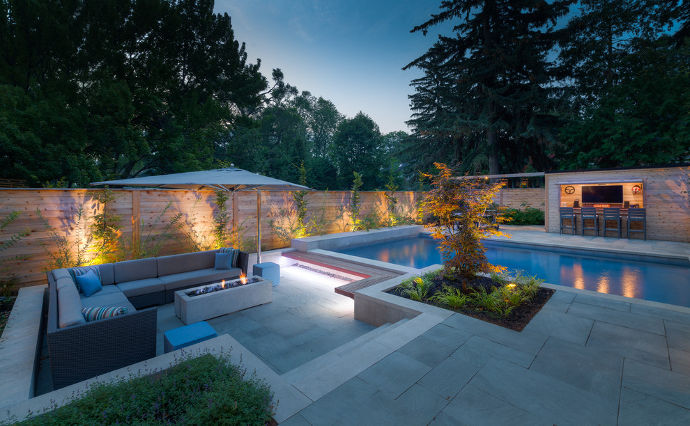 Photo of a large contemporary backyard rectangular pool in Other with a pool house and natural stone pavers.