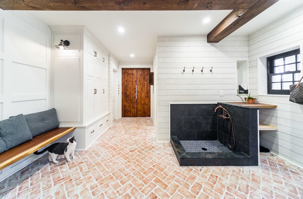 This is an example of a large country mudroom in Philadelphia with white walls, brick floors, a single front door, a gray front door and multi-coloured floor.