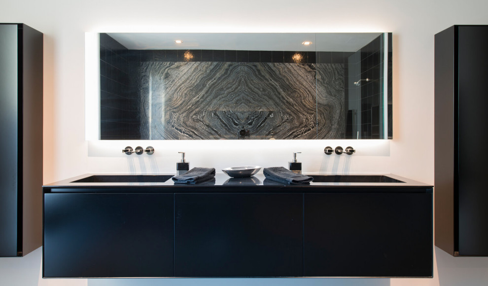 Inspiration for a medium sized modern ensuite bathroom in Los Angeles with black tiles, marble tiles, white walls, a submerged sink, black worktops, double sinks and a floating vanity unit.