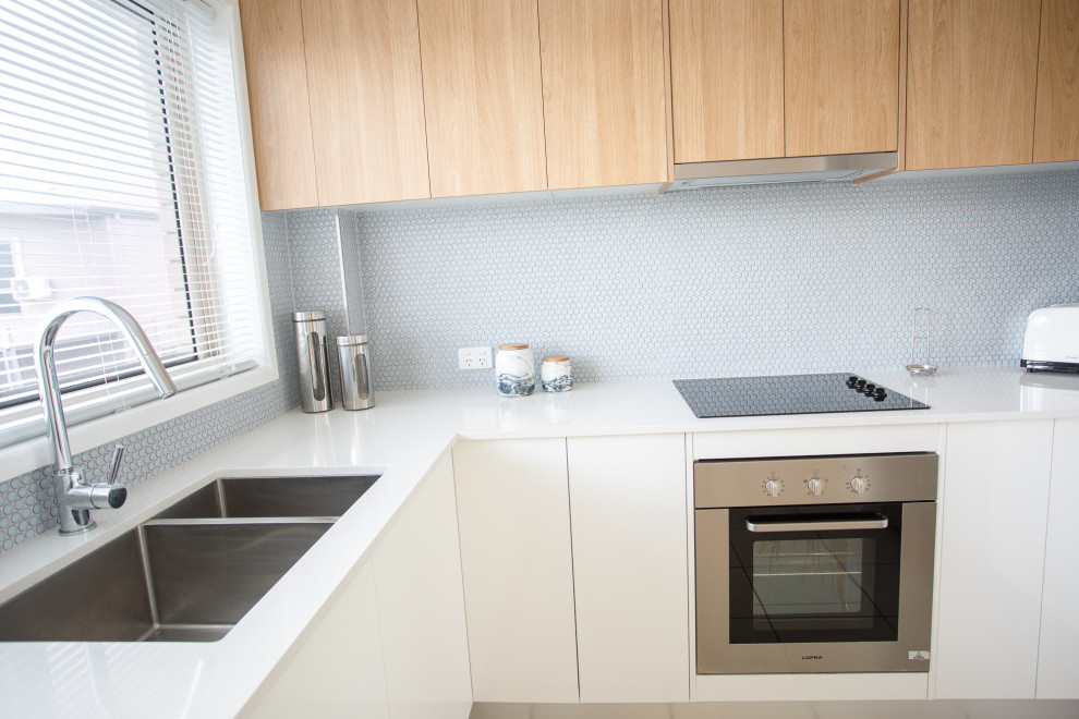This is an example of a scandinavian u-shaped eat-in kitchen in Gold Coast - Tweed with an undermount sink, light wood cabinets, blue splashback, ceramic splashback, stainless steel appliances, ceramic floors, no island and beige floor.