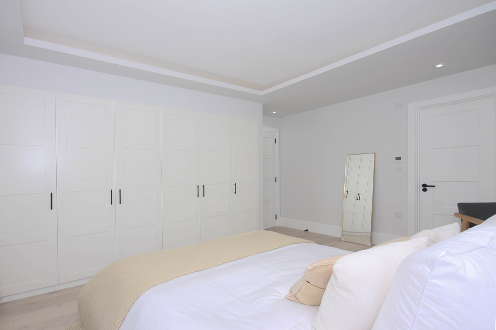 This is an example of a mid-sized contemporary master bedroom in London with grey walls, medium hardwood floors and white floor.