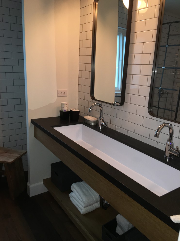 This is an example of a mid-sized industrial master bathroom in Los Angeles with open cabinets, an open shower, white tile, subway tile, white walls, a trough sink and solid surface benchtops.