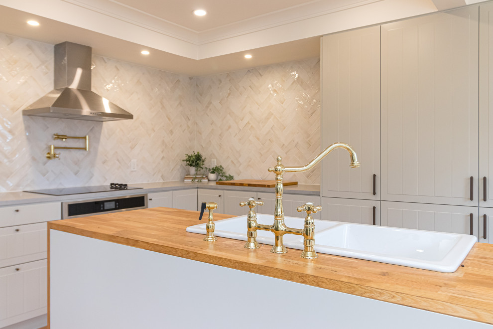 Eat-in kitchen - mid-sized transitional l-shaped medium tone wood floor, brown floor and coffered ceiling eat-in kitchen idea with a farmhouse sink, raised-panel cabinets, gray cabinets, wood countertops, beige backsplash, ceramic backsplash, stainless steel appliances, an island and brown countertops