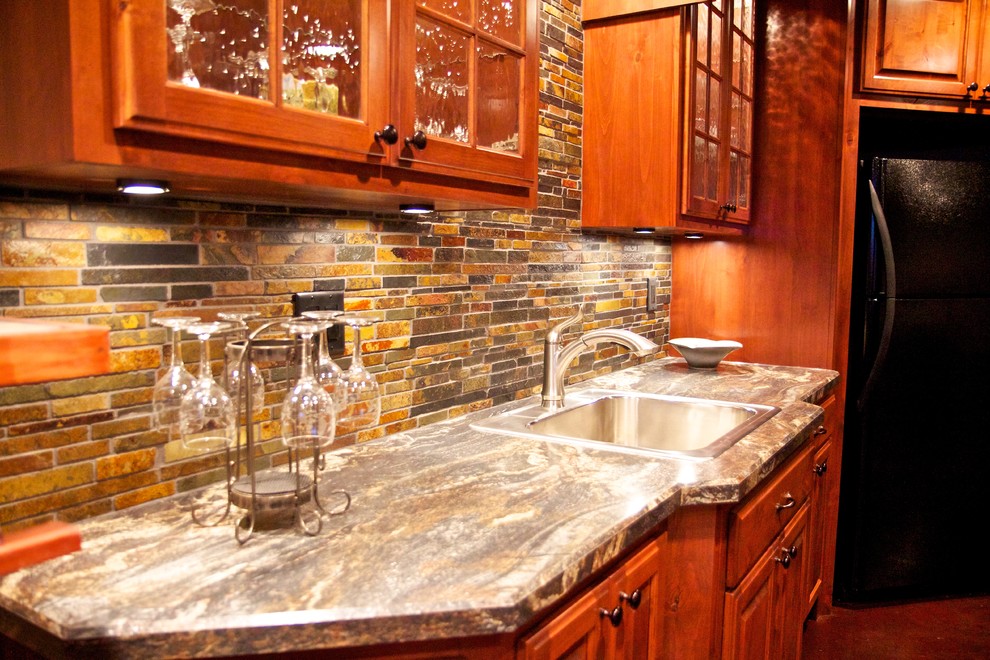 Open concept kitchen - mid-sized l-shaped concrete floor open concept kitchen idea with a drop-in sink, raised-panel cabinets, medium tone wood cabinets, laminate countertops, multicolored backsplash, stone tile backsplash and stainless steel appliances