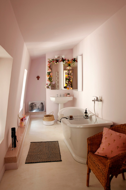 This is an example of a medium sized contemporary ensuite bathroom in Paris with recessed-panel cabinets, a built-in bath, a wall mounted toilet, pink tiles, pink walls, concrete flooring, beige floors, an enclosed toilet, a single sink and a built in vanity unit.