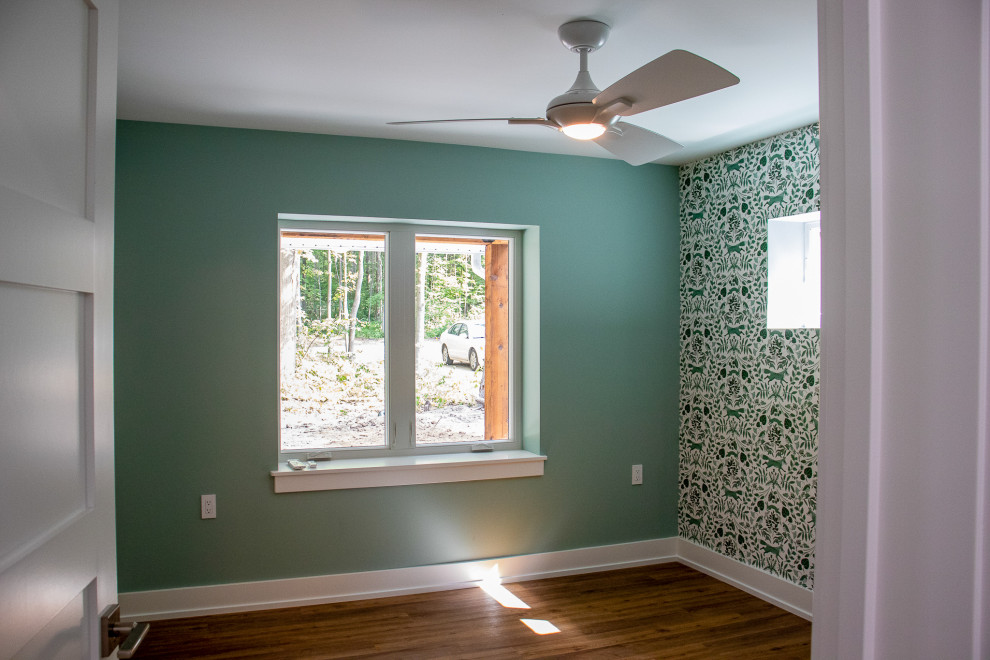 Large modern guest bedroom in Grand Rapids with green walls, laminate floors, green floors, wallpapered walls and a feature wall.