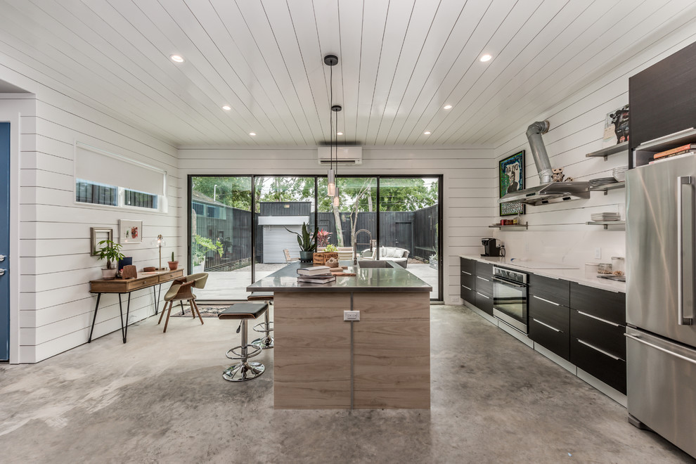 Photo of a small modern galley eat-in kitchen in Houston with an integrated sink, flat-panel cabinets, dark wood cabinets, stainless steel benchtops, white splashback, stone slab splashback, stainless steel appliances, concrete floors, with island, grey floor and grey benchtop.