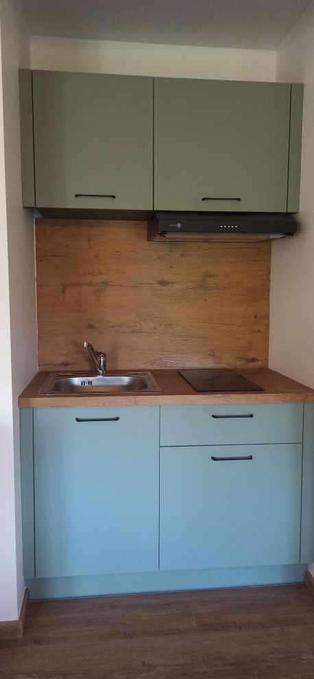 Photo of a small scandi single-wall open plan kitchen in Other with a submerged sink, beaded cabinets, green cabinets, laminate countertops, brown splashback, wood splashback, stainless steel appliances, light hardwood flooring, no island, brown floors and brown worktops.
