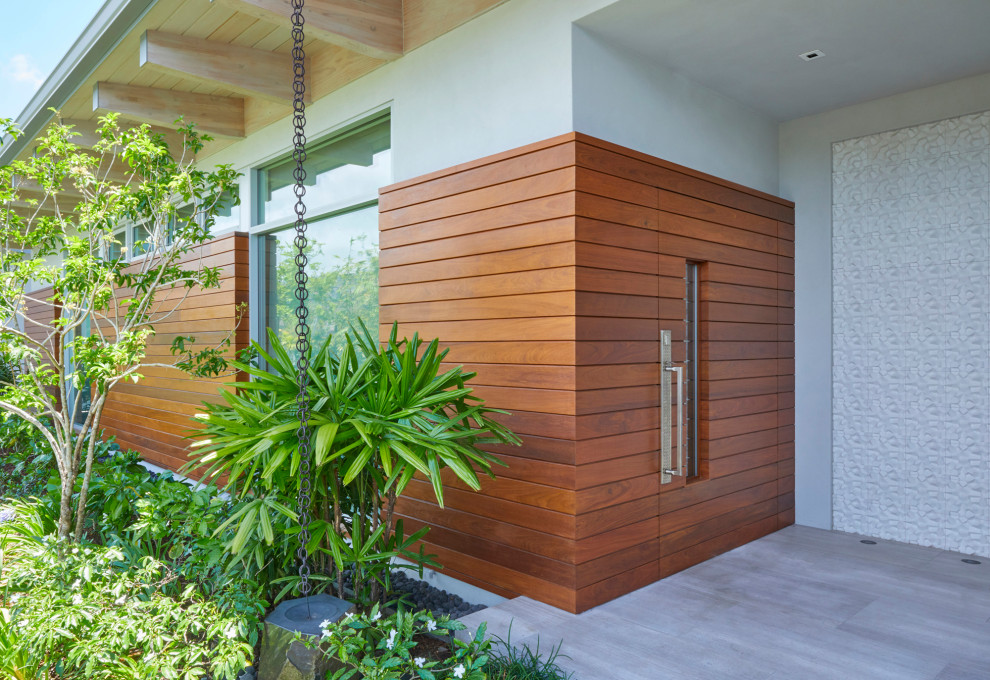Inspiration for a mid-sized tropical front door in Hawaii with white walls, a pivot front door, a brown front door, exposed beam and wood walls.