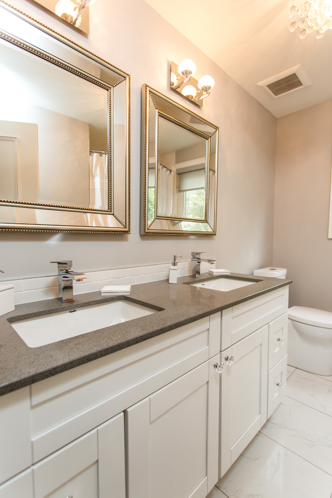 This is an example of a modern bathroom in Toronto with an undermount sink, flat-panel cabinets, white cabinets, granite benchtops, an alcove shower, a two-piece toilet, grey walls and ceramic floors.