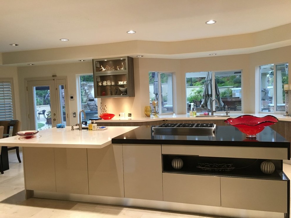 Example of a large transitional u-shaped marble floor eat-in kitchen design in Orange County with a double-bowl sink, flat-panel cabinets, white cabinets, solid surface countertops and stainless steel appliances