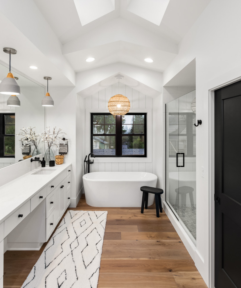 Photo of a large transitional master bathroom in Los Angeles with shaker cabinets, white cabinets, a freestanding tub, a shower/bathtub combo, a one-piece toilet, white walls, ceramic floors, a drop-in sink, engineered quartz benchtops, white floor, a hinged shower door, white benchtops, a double vanity and a built-in vanity.