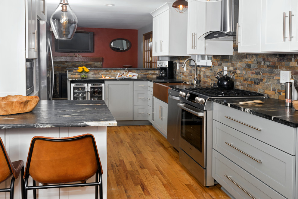 Inspiration for a mid-sized transitional u-shaped medium tone wood floor and beige floor eat-in kitchen remodel with a farmhouse sink, shaker cabinets, gray cabinets, marble countertops, multicolored backsplash, stone tile backsplash, stainless steel appliances, a peninsula and black countertops