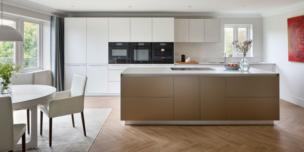 Modern inredning av ett mellanstort linjärt kök och matrum, med en integrerad diskho, släta luckor, laminatbänkskiva, svarta vitvaror, klinkergolv i porslin, en köksö och brunt golv