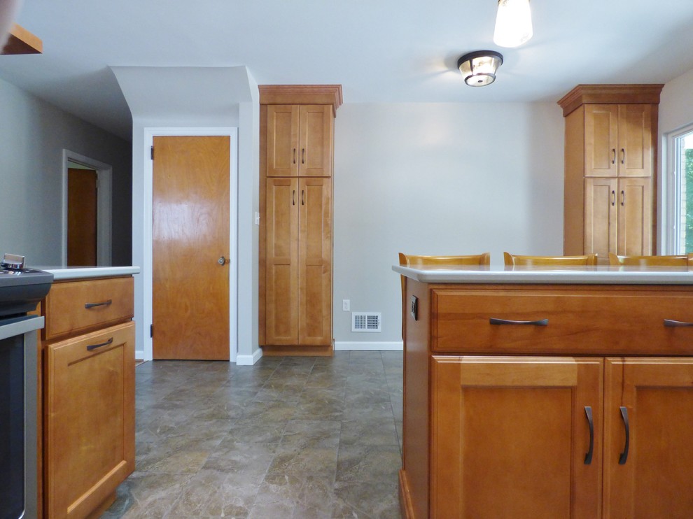 Inspiration for a transitional l-shaped porcelain tile eat-in kitchen remodel with an undermount sink, recessed-panel cabinets, medium tone wood cabinets, quartz countertops, white backsplash, subway tile backsplash, stainless steel appliances and an island
