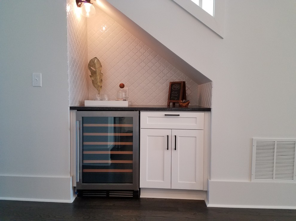 Design ideas for a small transitional single-wall wet bar in Atlanta with no sink, shaker cabinets, white cabinets, solid surface benchtops, white splashback, ceramic splashback and dark hardwood floors.