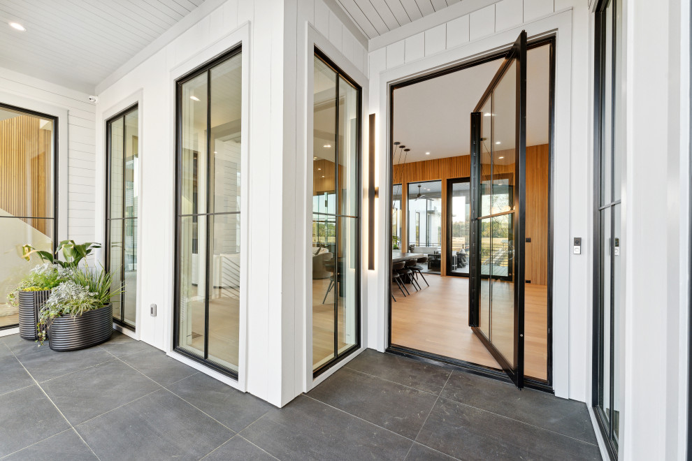 Geräumige Moderne Haustür mit weißer Wandfarbe, Porzellan-Bodenfliesen, Drehtür, schwarzer Haustür, schwarzem Boden, Holzdielendecke und Holzdielenwänden in Charleston