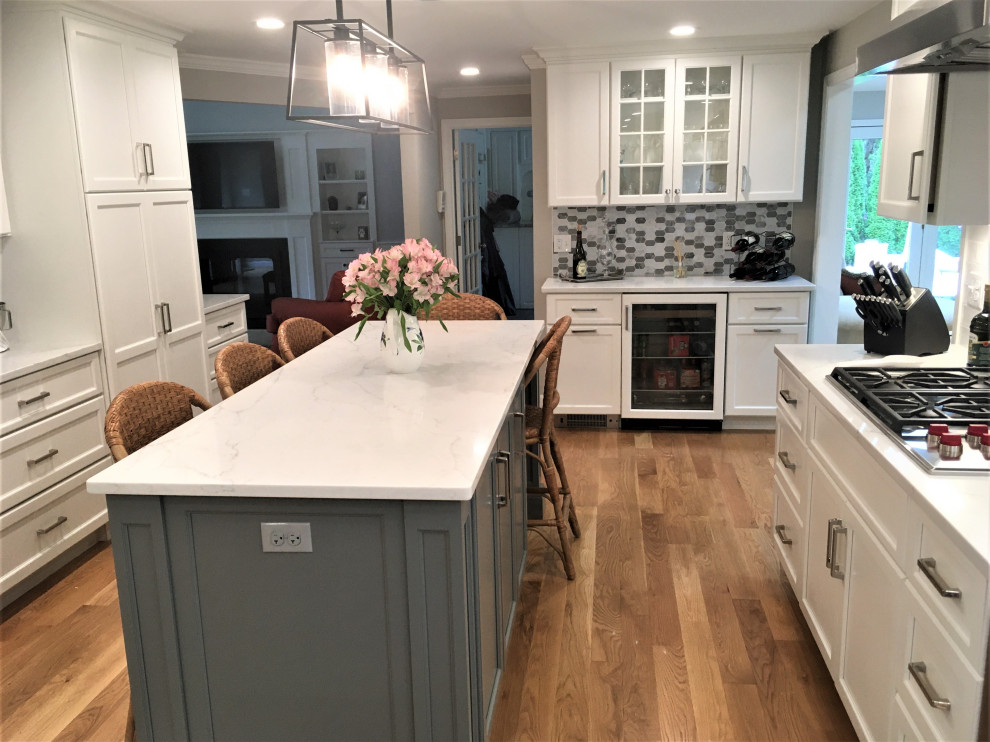 Large transitional galley light wood floor and brown floor eat-in kitchen photo in Boston with an undermount sink, shaker cabinets, white cabinets, quartz countertops, white backsplash, subway tile backsplash, stainless steel appliances, two islands and white countertops