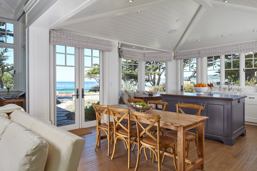 Design ideas for a mid-sized beach style open plan dining in San Francisco with medium hardwood floors, white walls, a standard fireplace and a stone fireplace surround.